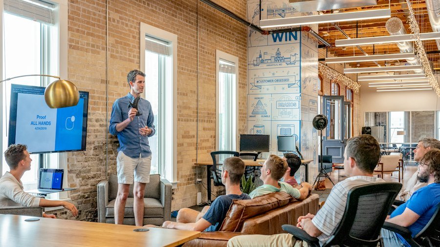 Presenter speaking to a group in a brick-walled office