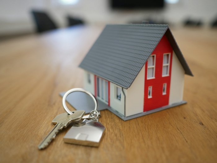 Small model house and keys on a wooden table