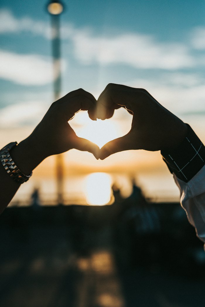 Hands forming a heart shape at sunset
